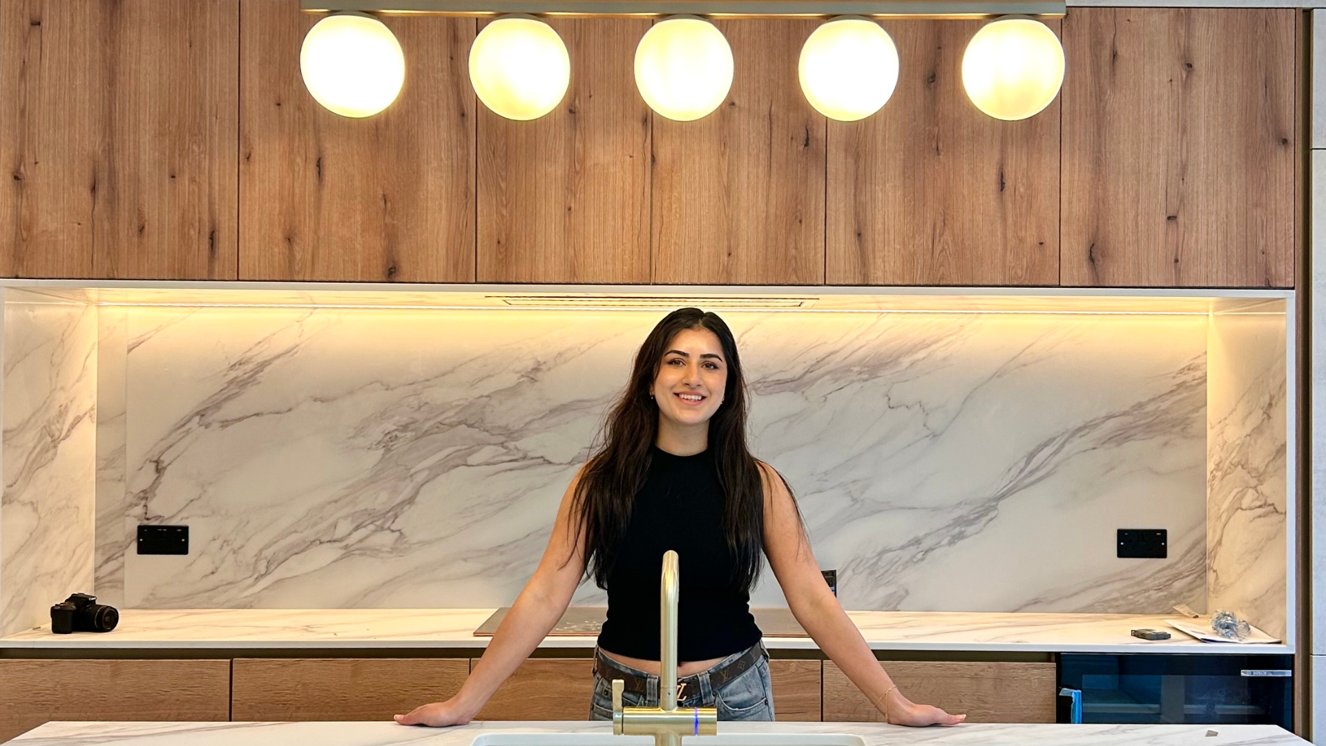 Karisma Shoker standing in a kitchen with bulb lighting at a marble kitchen island
